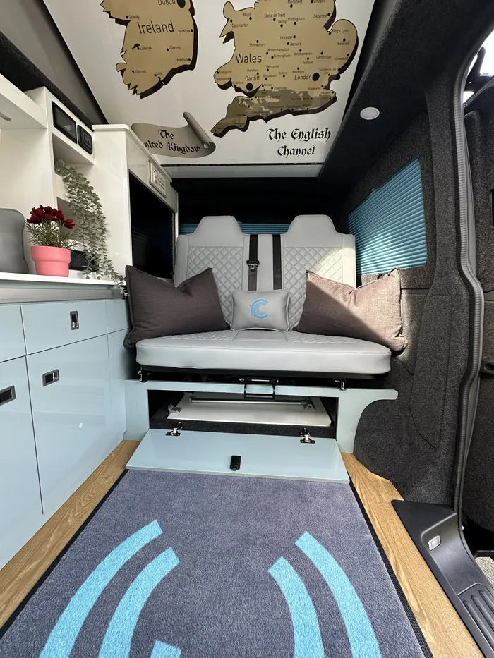Inside Enola, the blue kitchen and rock and roll bed beneath a UK map roof print