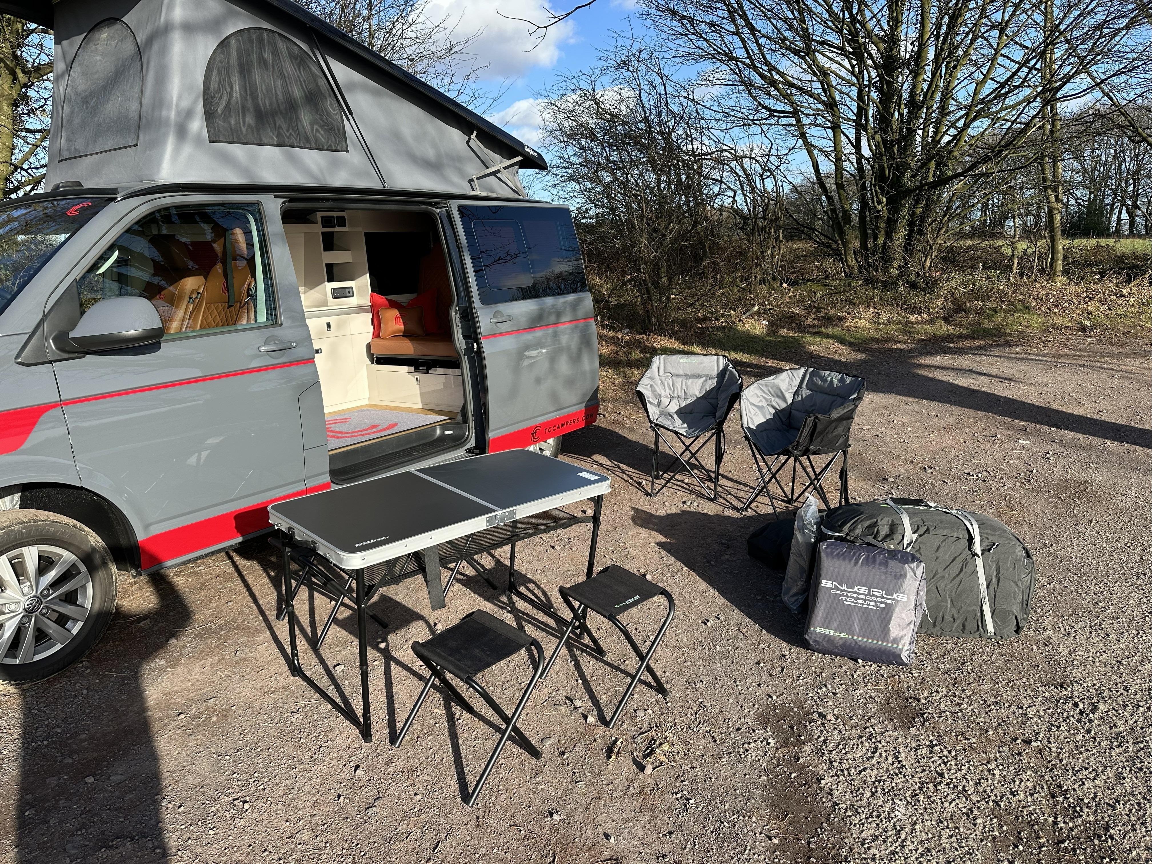 Fenyx parked up with the camping table, chairs and awning bag set out beside it